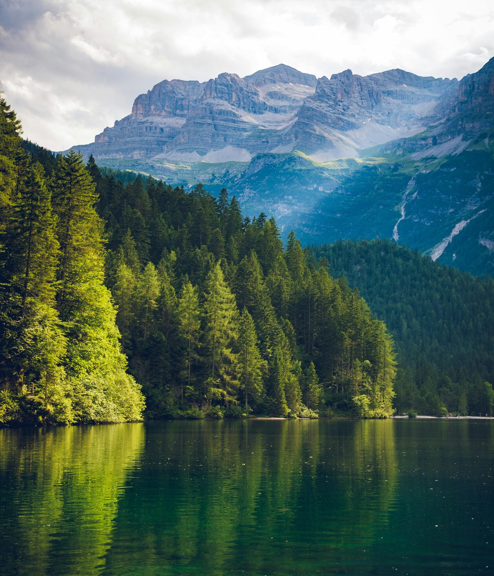 Peaceful alpine landscape featuring a serene lake with mountain and forest reflections.
